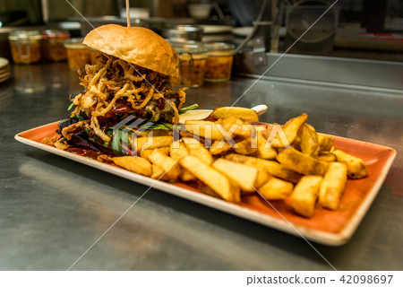 Home made hamburger with lettuce, cheese, beef meat and french fries placed on stainless steel table Home made hamburger with lettuce, cheese, beef meat and french fries placed on stainless steel table 42098697