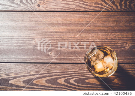 Glass of whiskey on an old wooden table Glass of whiskey on an old wooden table 42100486