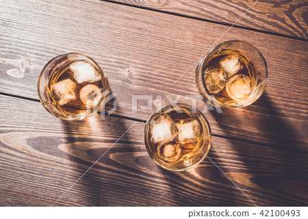 Glasses of whiskey on an old wooden table Glasses of whiskey on an old wooden table 42100493
