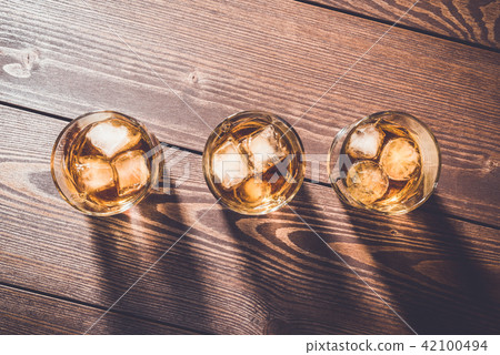 Glasses of whiskey on an old wooden table Glasses of whiskey on an old wooden table 42100494