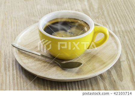 Instant coffee in yellow mug above wooden plate 42103714