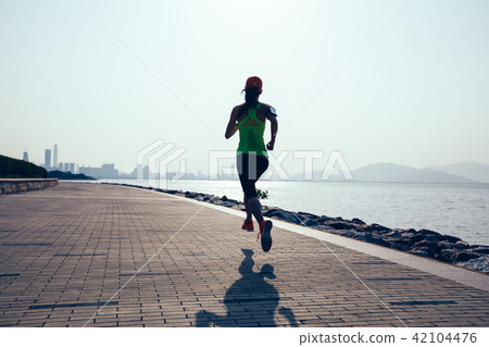 young fitness woman running on sunrise coast trail 42104476