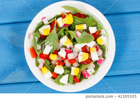 Fresh prepared salad in glass bowl on blue boards Fresh prepared salad in glass bowl on blue boards 42105105
