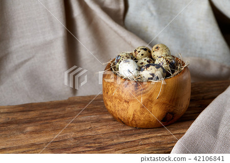Quail eggs in a wooden bowl on a homespun tablecloth, top view, close-up Quail eggs in a wooden bowl on a homespun tablecloth, top view, close-up 42106841