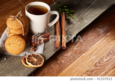 Traditional Christmas tea concept with a cup of hot tea, cookies and decorations on a wooden table Traditional Christmas tea concept with a cup of hot tea, cookies and decorations on a wooden table 42107023