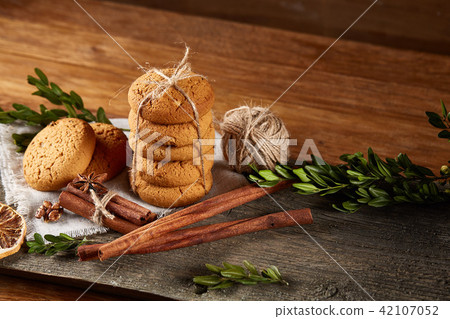 Christmas composition with pile of cookies, cinnamon and dried oranges on light wooden background 42107052