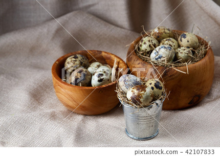 Quail eggs in a wooden bowl on a homespun tablecloth, top view, close-up Quail eggs in a wooden bowl on a homespun tablecloth, top view, close-up 42107833
