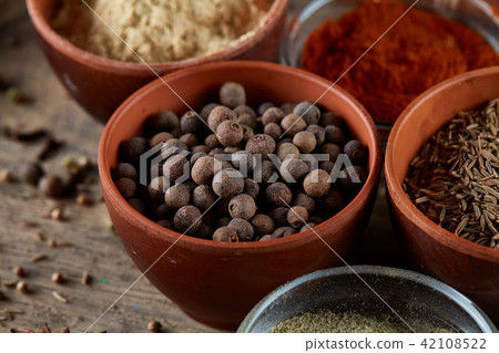 Spices in ceramic and glass bowls on the top of wooden barrel, close-up, selective focus. 42108522