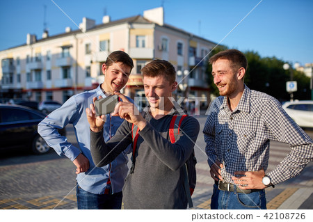 Portrait of a group of smiling friends, preparing for making selfie on camera on urban background. Portrait of a group of smiling friends, preparing for making selfie on camera on urban background. 42108726