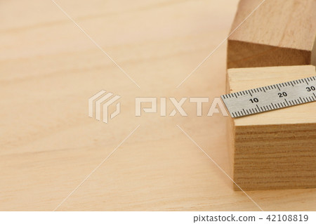 立方體木頭和金屬尺子(直標尺)放在木板上。 立方體木頭和金屬尺子(直標尺)放在木板上。 42108819