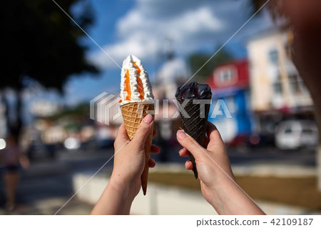 A first person view, female walking along the road with an ice cream in her hands, shallow depth of A first person view, female walking along the road with an ice cream in her hands, shallow depth of 42109187
