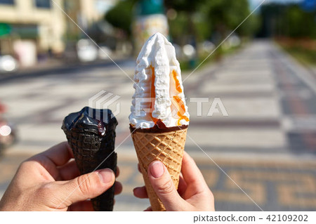 A first person view, sweethearts walking along the road with an ice cream in their hands, shallow A first person view, sweethearts walking along the road with an ice cream in their hands, shallow 42109202