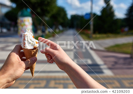 A first person view, sweethearts walking along the road with an ice cream in their hands, shallow A first person view, sweethearts walking along the road with an ice cream in their hands, shallow 42109203