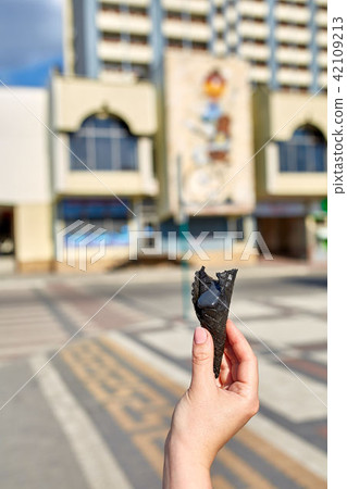 A first person view, a person walking along the road with an ice cream in his hands, shallow depth 42109213