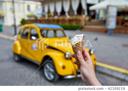 A first person view, a person walking along the road with an ice cream in his hands, shallow depth 42109219
