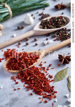 Red hot chillies pepper flakes in wooden spoon on white textured background, top view, close-up Red hot chillies pepper flakes in wooden spoon on white textured background, top view, close-up 42109334