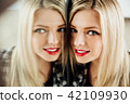 portrait of beautiful young woman blonde girl and her reflection in mirror. 42109930