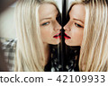 portrait of beautiful young woman blonde girl and her reflection in mirror. 42109933