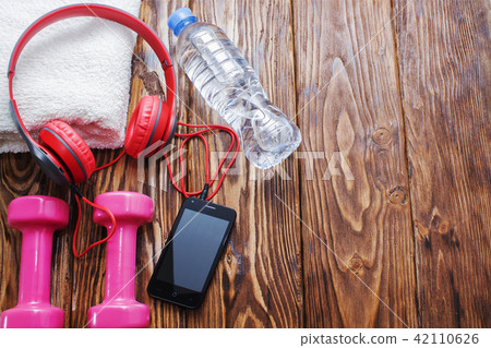 dumbbells and a bottle of water with towel on wooden background, concept preparing to fitness sports dumbbells and a bottle of water with towel on wooden background, concept preparing to fitness sports 42110626