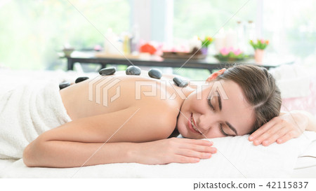 Hot stone massage treatment by therapist in spa. 42115837