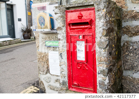 British red post embedded in the stone wall In a country town in the western end of the UK British red post embedded in the stone wall In a country town in the western end of the UK 42117377