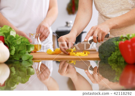 Closeup of human hands cooking in kitchen. Mother and daughter or two female friends cutting 42118292