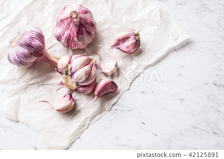 Garlic Cloves and Bulbs on white marble board Garlic Cloves and Bulbs on white marble board 42125891