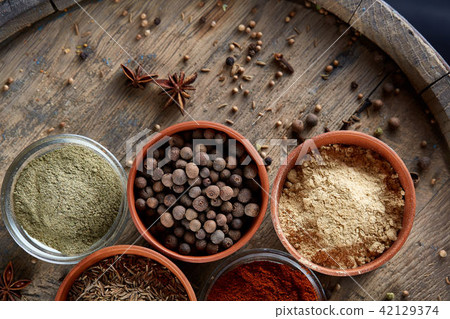 Spices in ceramic bowls on the top of wooden barrel, close-up, selective focus, vertical. 42129374