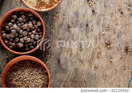 Spices in ceramic bowls on the top of wooden barrel, close-up, selective focus, vertical. 42129392