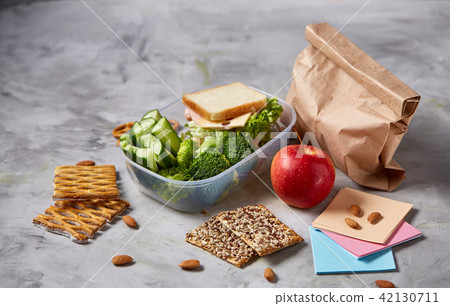 School or picnic lunch box with sandwich and various colorful vegetables and fruits on wooden 42130711