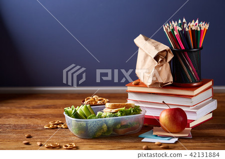 Concept of school lunch break with healthy lunch box and school supplies on white desk, selective Concept of school lunch break with healthy lunch box and school supplies on white desk, selective 42131884