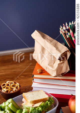 Concept of school lunch break with healthy lunch box and school supplies on white desk, selective Concept of school lunch break with healthy lunch box and school supplies on white desk, selective 42131886