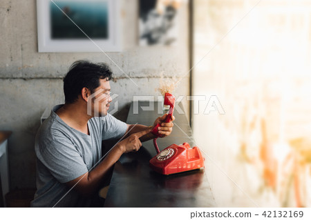 Asian man shy waiting phone call in a coffee shop Asian man shy waiting phone call in a coffee shop 42132169