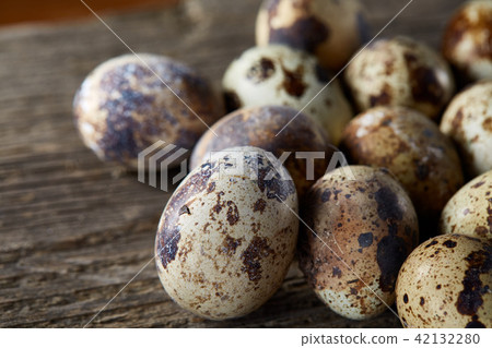 Spotted quail eggs arranged on the background of old wooden boards, with copy-space, selective focus 42132280