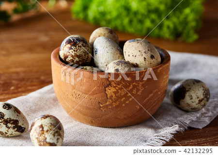 Quail eggs in the box on napkin with green blurred natural leaves background, selective focus, close 42132295