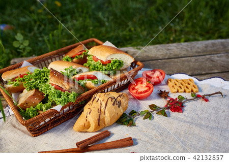 Picnic on a green lawn, pastries and vegetables on a homespun tablecloth, summer season, flat lay Picnic on a green lawn, pastries and vegetables on a homespun tablecloth, summer season, flat lay 42132857