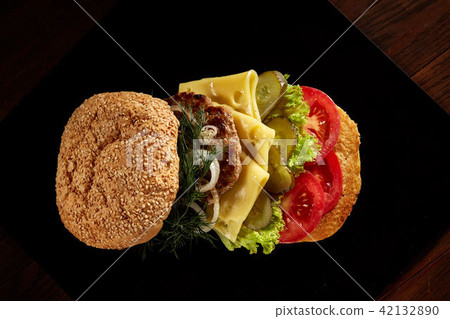 Big fresh burger on black plate on wooden background. Big fresh burger on black plate on wooden background. 42132890