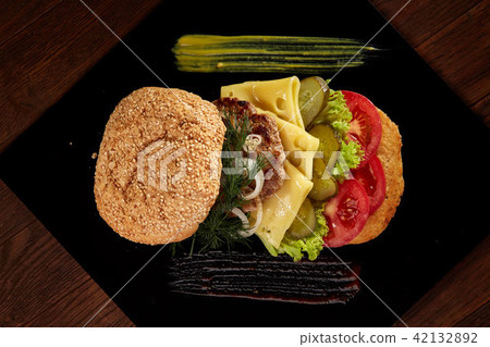 Big fresh burger with sauce on black plate on wooden background. 42132892