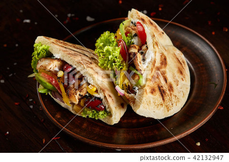 Pita stuffed with chicken, beans and letucce on clay plate over wooden background, side view 42132947