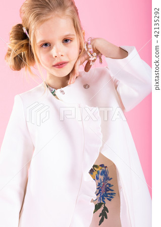 A teenage girl in light clothes posing on a pink background. 42135292