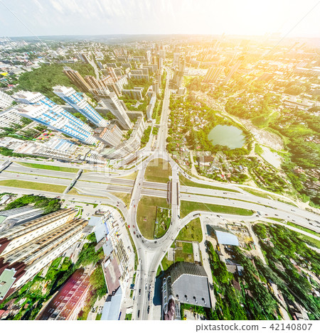 Aerial city view with crossroads and roads, houses, buildings, parks and parking lots. Sunny summer Aerial city view with crossroads and roads, houses, buildings, parks and parking lots. Sunny summer 42140807
