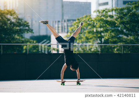 Skateboarder practice handstand on skateboad Skateboarder practice handstand on skateboad 42140811