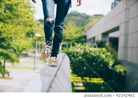 walking on the edge of a urban building wall 42142461