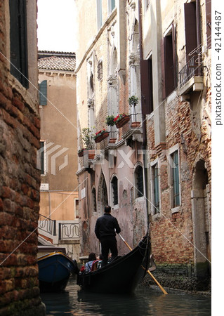 橫渡一條美麗的運河的威尼斯式長平底船 橫渡一條美麗的運河的威尼斯式長平底船 42144487