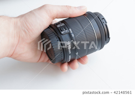 Hand holding camera lens on white background 42148561