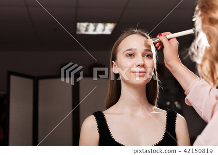 makeup artist applying foundation on a forehead of a girl 42150819