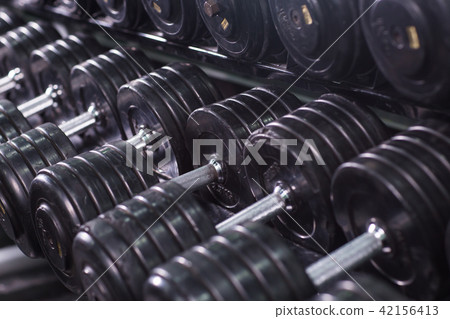 Black dumbbell set in sport fitness center. Weight Training Equipment concept. Black dumbbell set in sport fitness center. Weight Training Equipment concept. 42156413