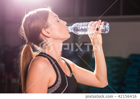 Fitness young woman drinking water from bottle. Muscular young female at gym taking a break from 42156416
