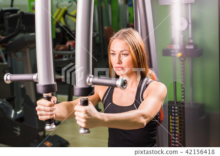 Young woman doing butterfly exercise in the fitness center. 42156418