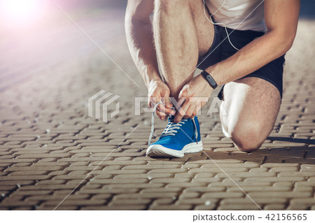 Fit athlete tying shoe during running 42156565
